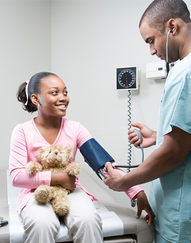 male nurse taking blood pressure from little girl
